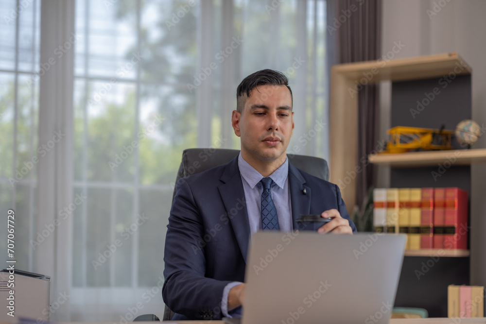 Male manager in suit multitask on laptop, tablet in modern office, talk to clients, analyze project Male manager in suit multitask on laptop, tablet in modern office, talk to clients, analyze project
