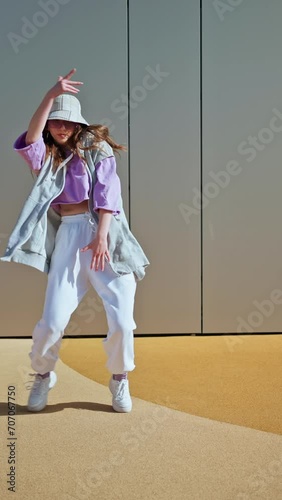 Young hip hop girl in oversize outfit wearing dancing into music minimalistic urban background. Hip-hop queen. Breakdancer woman. minimalistic 