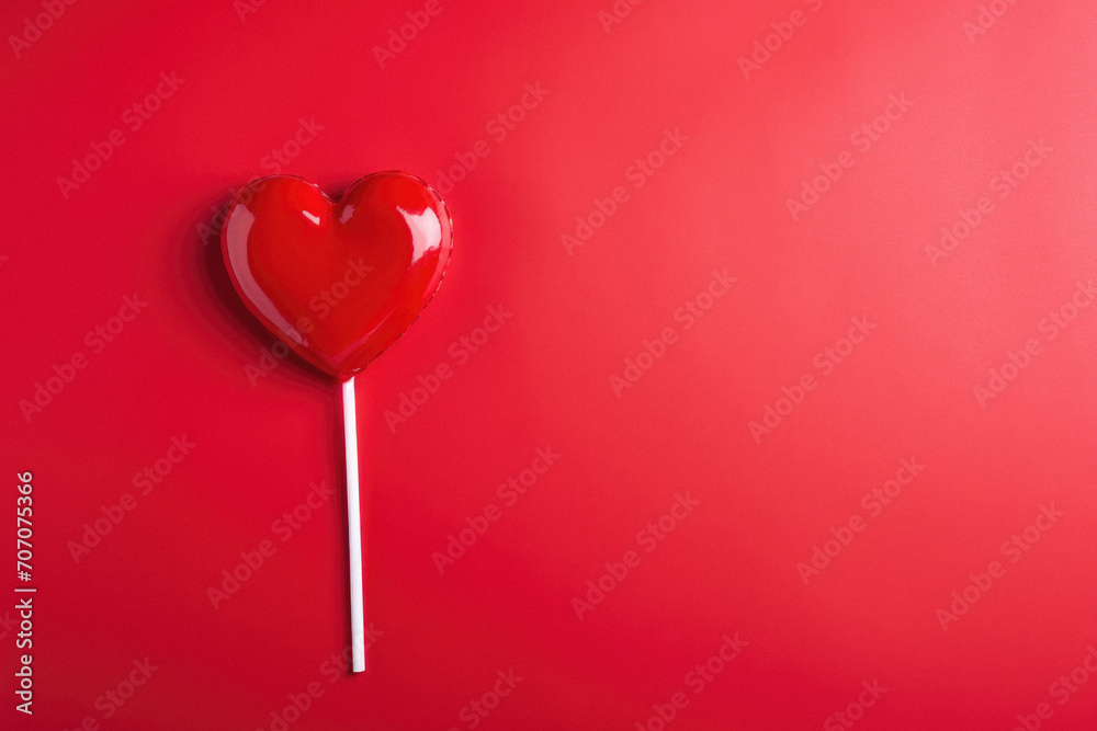 Red heart shaped lollipop on red background. Valentines day concept.