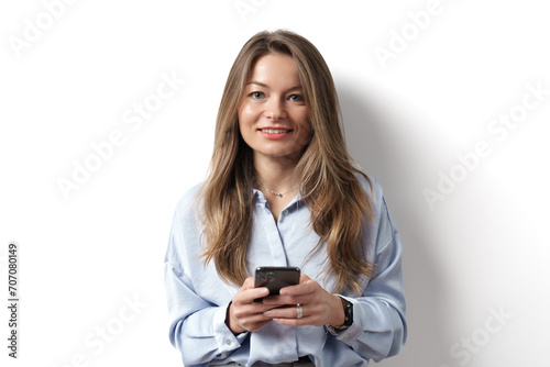 A friendly, young businesswoman in a blue shirt engaging with her smartphone, against a bright white background