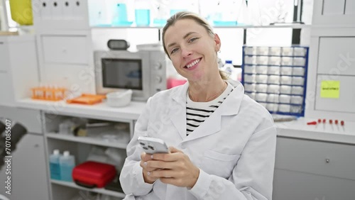 A smiling woman scientist using smartphone in a laboratory setting, evoking professionalism and modern technology. photo