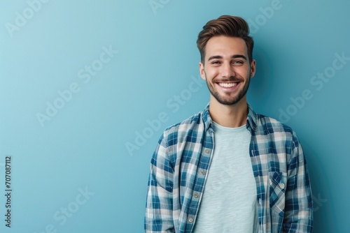 Portrait of a handsome man with a friendly smile, wearing a smart casual outfit, standing against a plain blue background. photo