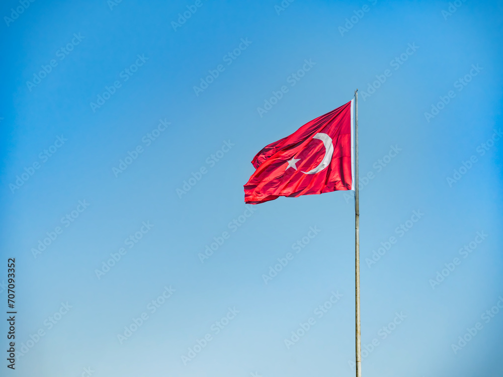 Close-up of a Turkish flag on a flagpole fluttering in the wind against a blue sky. Copy space. No people. Close-up of a Turkish flag on a flagpole fluttering in the wind against a blue sky. Copy space. No people.