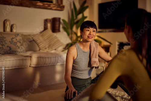 A smiling Asian female yoga instructor, talking with her female client, after yoga class.