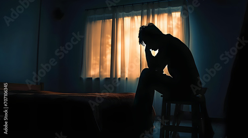 Silhouette depressed man sadly sitting on the bed in the bedroom. Sad asian man suffering depression insomnia awake and sit alone on the bed in bedroom. Depression health people concept.