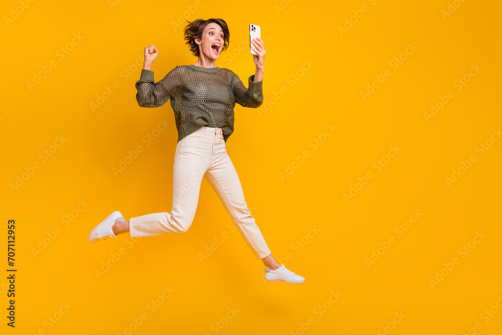 Photo of overjoyed excited girl wear trendy clothes going empty space talking video call isolated on yellow color background Photo of overjoyed excited girl wear trendy clothes going empty space talking video call isolated on yellow color background