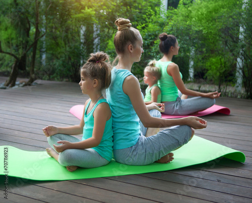 Fototapeta Naklejka Na Ścianę i Meble -  Mothers and daughters doing exercise practicing yoga outdoors