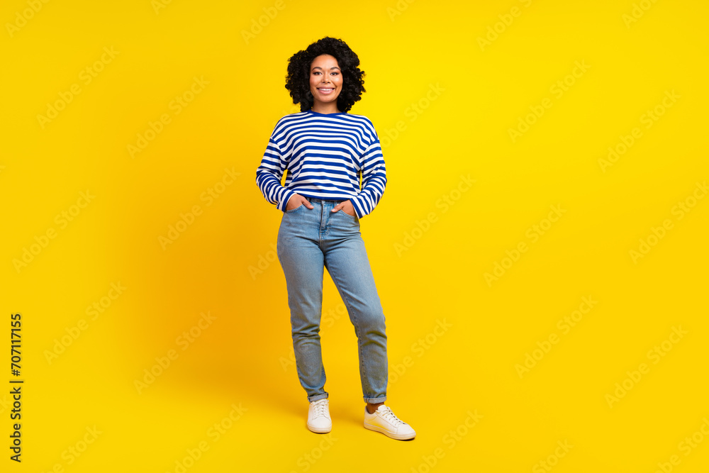 Full size photo of optimistic woman dressed striped sweatshirt denim pants keep palms in pockets isolated on yellow color background Full size photo of optimistic woman dressed striped sweatshirt denim pants keep palms in pockets isolated on yellow color background