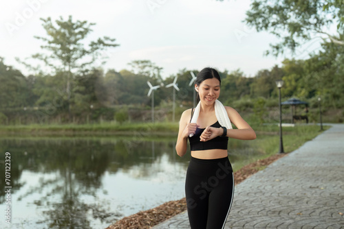 Sport young woman looking at smartwatch on her wrist, tracking fitness activity during training outdoors