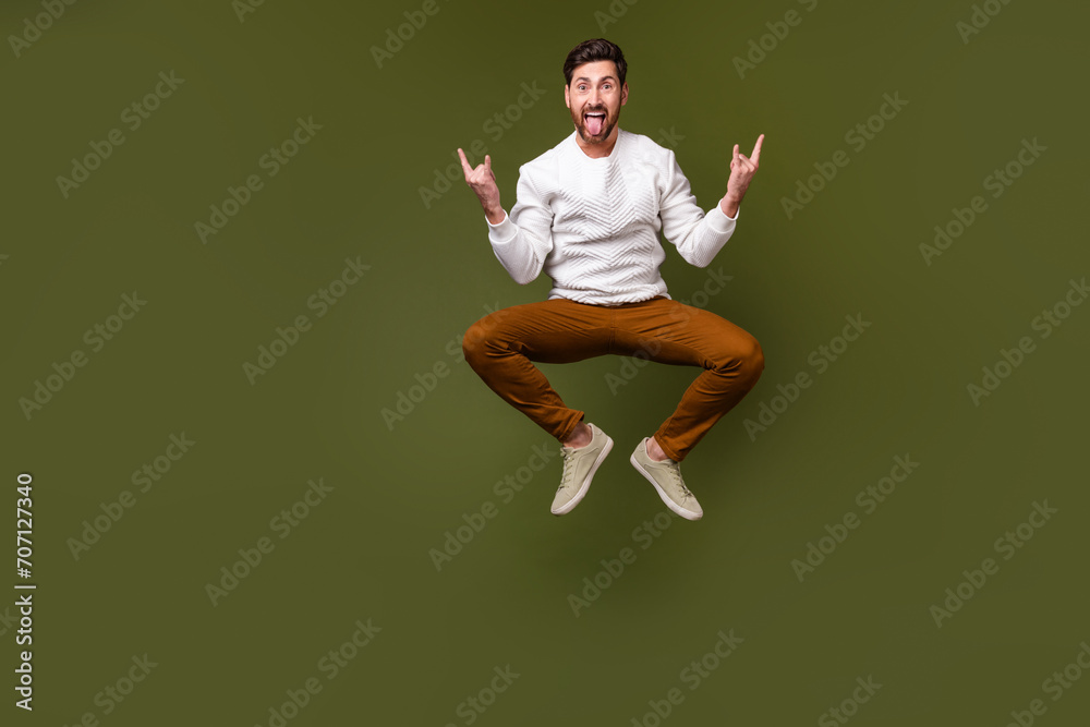 Full length photo of overjoyed glad man celebrating holiday rock n roll concert festival isolated on khaki color background Full length photo of overjoyed glad man celebrating holiday rock n roll concert festival isolated on khaki color background
