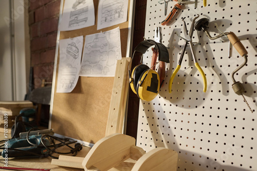 Close up of protection headphones and various tools on pegboard in carpenters workshop, copy space photo