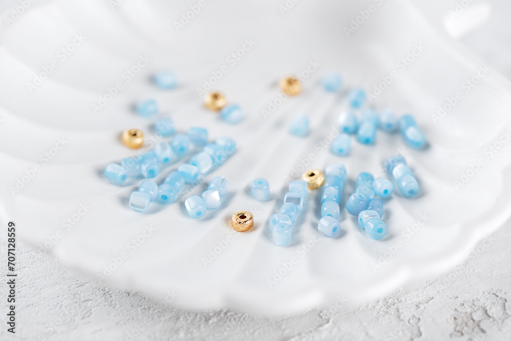 Blue mother-of-pearl and gold beads on a white tray, jewelry making. Blue mother-of-pearl and gold beads on a white tray, jewelry making.