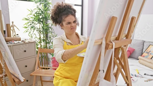 Intolerable stink in the studio! hispanic curly haired female artist sitting, smelling bad smell, holding breath with disgust on nose. offensively smelly situation photo