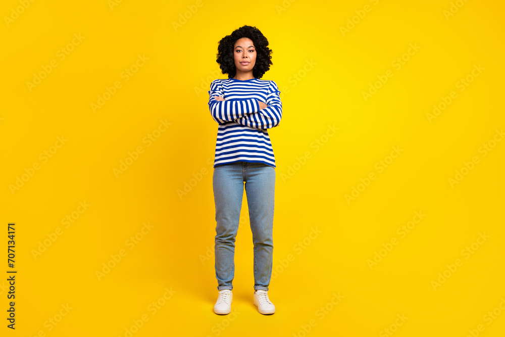 Full size photo of serious strict woman dressed striped sweatshirt denim pants hold arms crossed isolated on yellow color background Full size photo of serious strict woman dressed striped sweatshirt denim pants hold arms crossed isolated on yellow color background