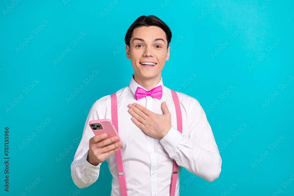 Photo portrait of attractive young man touch chest impressed device dressed stylish pink clothes isolated on aquamarine color background Photo portrait of attractive young man touch chest impressed device dressed stylish pink clothes isolated on aquamarine color background