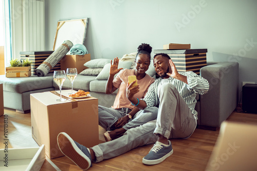Smiling young couple having video call after moving in new home photo