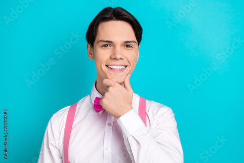 Photo portrait of handsome young guy touch chin minded cheerful dressed stylish pink garment isolated on aquamarine color background