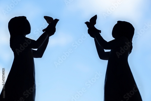 Photography silhouettes of two figures of girls with birds in their hands against the backgr
