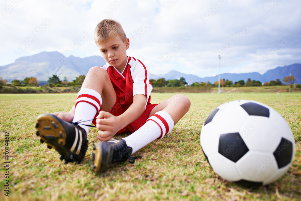 Boy, soccer player and ball with shoe laces, field and ready for game, shoes and child. Outdoor, playful and sport for childhood, person and athlete for match, alone and outside on football pitch Boy, soccer player and ball with shoe laces, field and ready for game, shoes and child. Outdoor, playful and sport for childhood, person and athlete for match, alone and outside on football pitch
