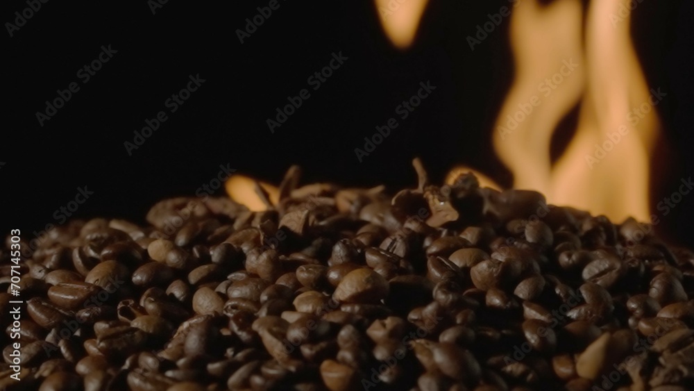 Fototapeta premium Coffee beans on a black studio background with burning tongues of flame. The process of roasting coffee to make an invigorating drink. Advertising concept for a coffee shop or restaurant.