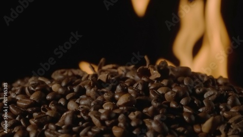 Coffee beans on a black studio background with burning tongues of flame. The process of roasting coffee to make an invigorating drink. Advertising concept for a coffee shop or restaurant.