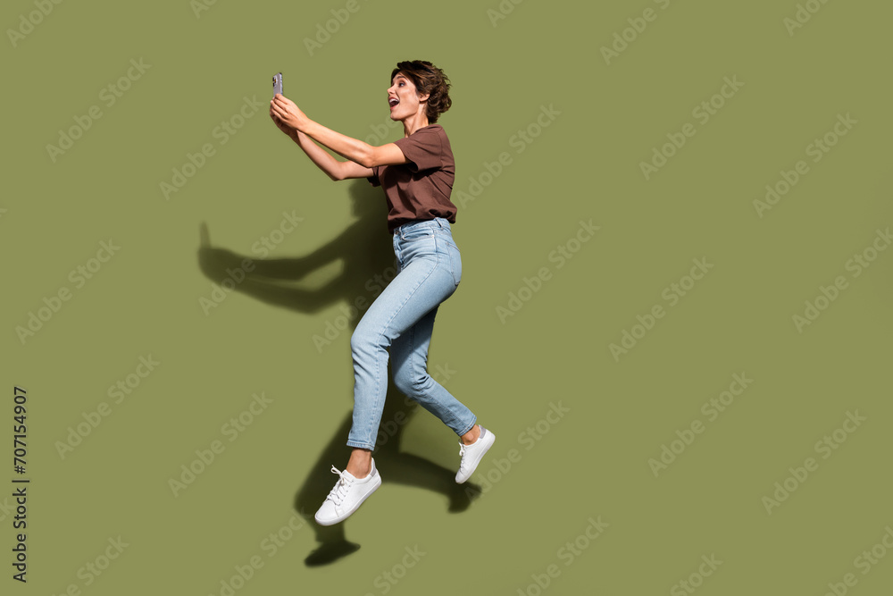 Full length photo of lovely young lady running video recording take selfie wear trendy brown garment isolated on khaki color background