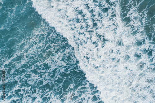 Aerial top view of white foam on the surface of the blue sea.