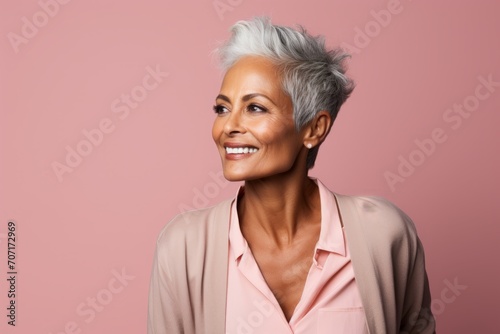 Portrait of a happy senior woman smiling and looking away against pink background