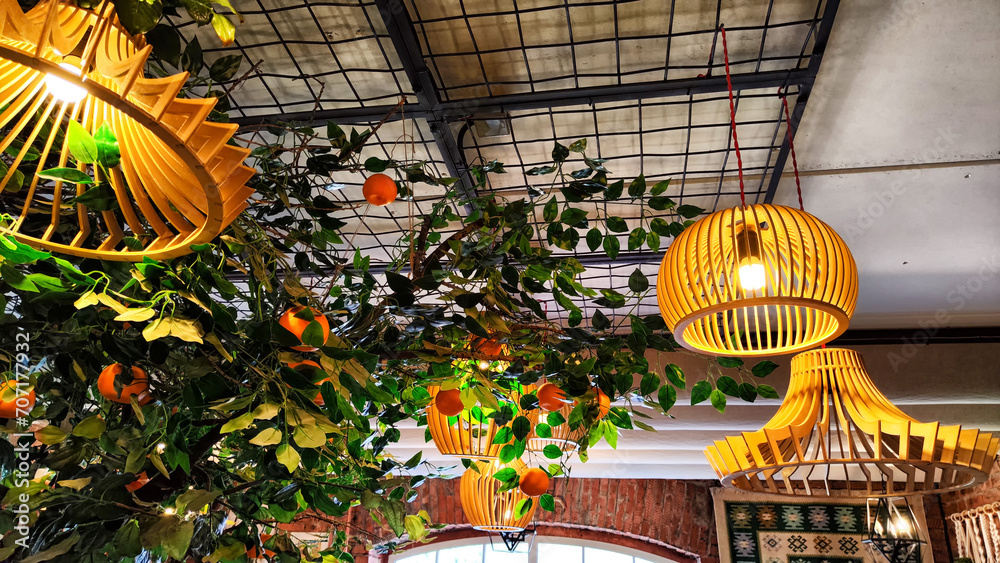 Obraz premium Yellow wicker chandeliers on the ceiling and orange tree with tangerines. Interior, room design, cute, warm background
