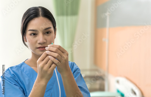 Asian nurse woman adjusting saline line for patient in hospital