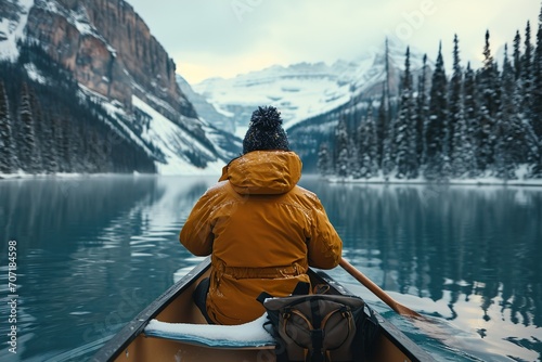 Male traveler in winter coat canoeing in Lake. photo