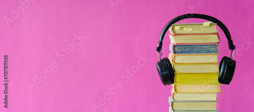 Relaxing with audiobooks concept with heap of books and vintage headphones.Bright pink background with large copy space