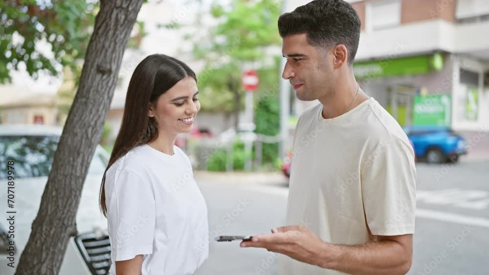 A happy couple engaging with a smartphone on a sunny urban street A happy couple engaging with a smartphone on a sunny urban street