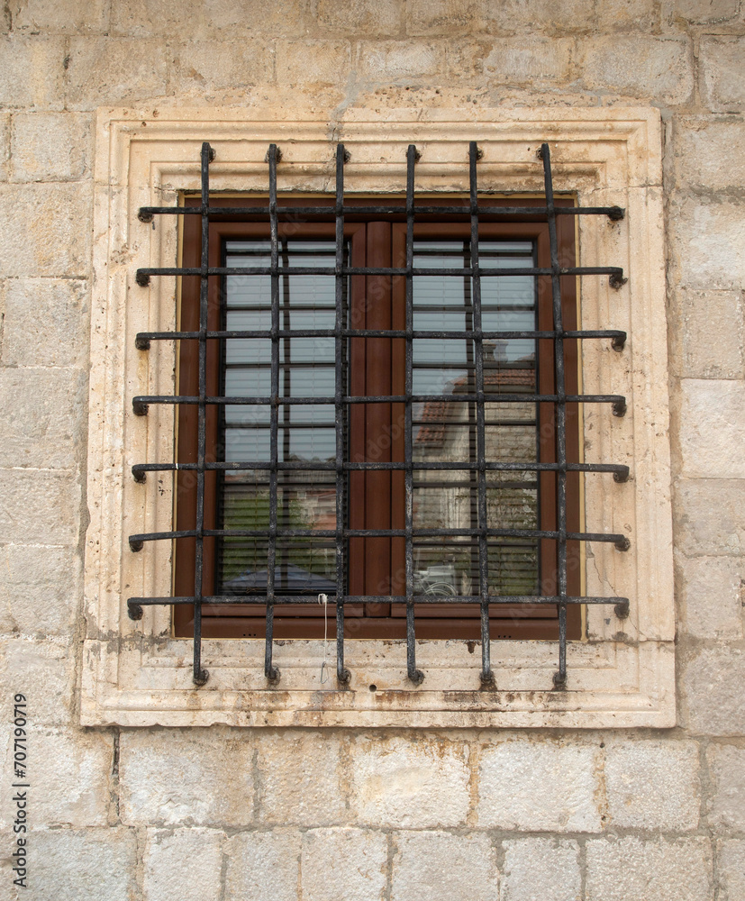 Old window  with metal grill on stone facade in Montenegro
