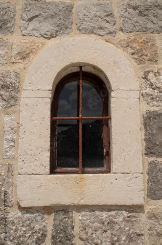Old arched window  with metal grill on stone facade in Montenegro