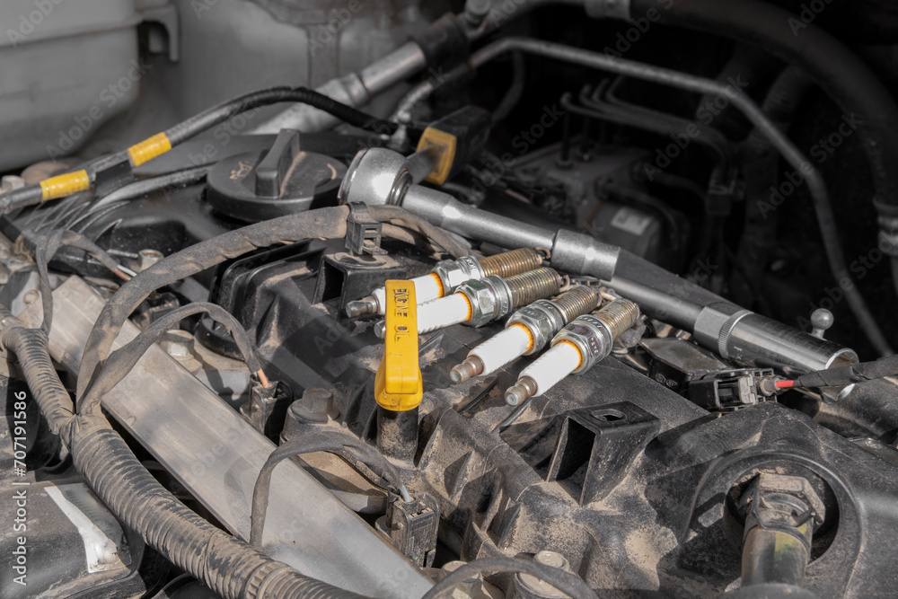 Spark plugs and a tool on the background of a car engine. Replacing spark plugs