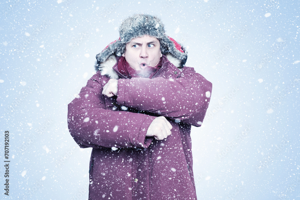 A frozen man in winter clothes waves his hands to keep warm, steam is coming out of his mouth, on a blue background with snow A frozen man in winter clothes waves his hands to keep warm, steam is coming out of his mouth, on a blue background with snow
