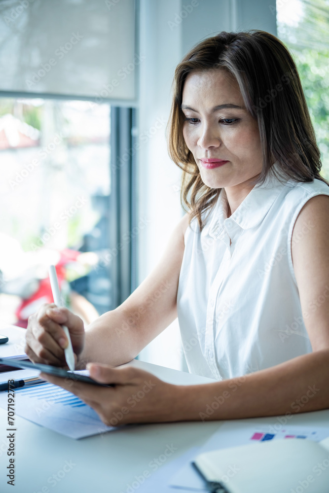 Businesswoman sitting at desk on couch in workplace or at home working on laptop and analyzing data on charts and graphs and writing on papers to make business plan and strategies for company, Businesswoman sitting at desk on couch in workplace or at home working on laptop and analyzing data on charts and graphs and writing on papers to make business plan and strategies for company,