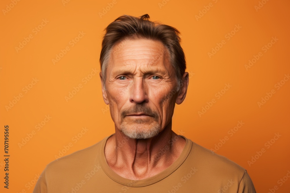 Portrait of a mature man looking at camera, isolated on orange background Portrait of a mature man looking at camera, isolated on orange background