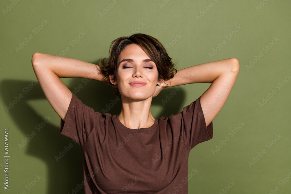 Photo portrait of lovely young lady hands behind head sleeping closed eyes wear trendy brown garment isolated on khaki color background Photo portrait of lovely young lady hands behind head sleeping closed eyes wear trendy brown garment isolated on khaki color background