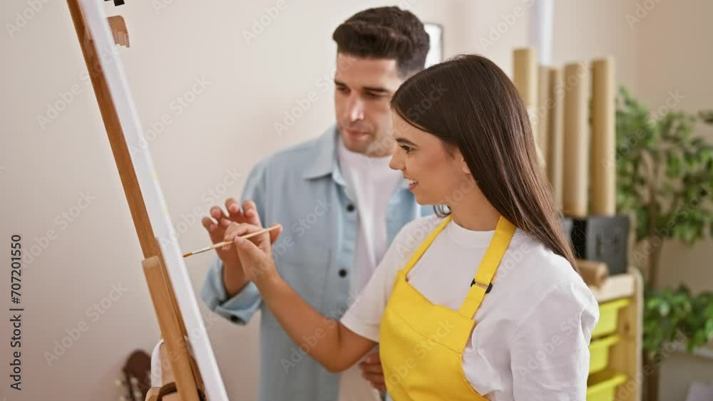A man and woman collaborate on a painting in a brightly lit studio, showcasing teamwork in an artistic environment. A man and woman collaborate on a painting in a brightly lit studio, showcasing teamwork in an artistic environment.