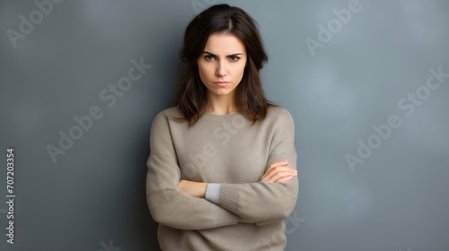 Mad female, angry adult woman standing with her arms crossed, and looking at the camera with an upset face expression. Unhappy lady, studio shot, annoyed and frustrated, negative emotions
