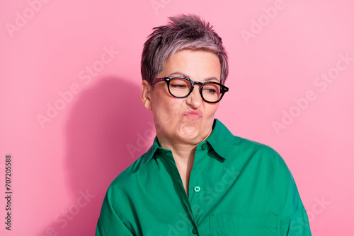 Photo portrait of lovely senior lady look disgusted wry face empty space wear trendy green garment isolated on pink color background photo