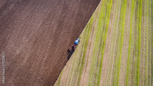 Canvas Print Drone photo of a blue tractor plowing the field