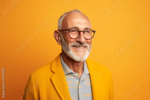 Portrait of smiling senior man in eyeglasses on orange background