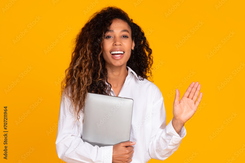 Cheerful african lady holding laptop computer gesturing hello greeting, studio Cheerful african lady holding laptop computer gesturing hello greeting, studio