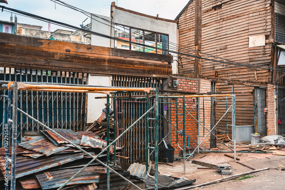 Naklejka premium Deconstruction of old wooden house. Demolish old wooden houses in Asian styles shophouses to improve area. The abandoned and dilapidated Asian old style shophouses. Demolition home. Selective focus.