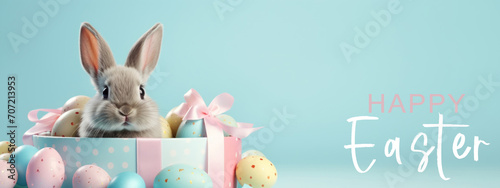 Happy easter concept holiday celebration greeting card with text - Cool easter bunny, rabbit, sitting in gift box with many colorful painted easter eggs, isolated on blue background photo
