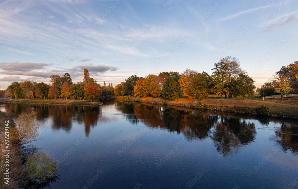 Autumn landscape with river and trees in the park at sunset.