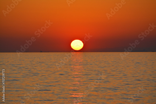 Fototapeta Naklejka Na Ścianę i Meble -  地平線に沈む夕日 快晴の空 穏やかな海